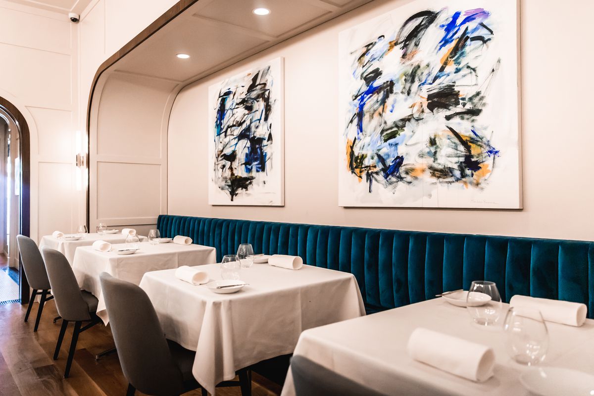 Sala da pranzo semplice ed elegante con dipinti astratti blu alle pareti.