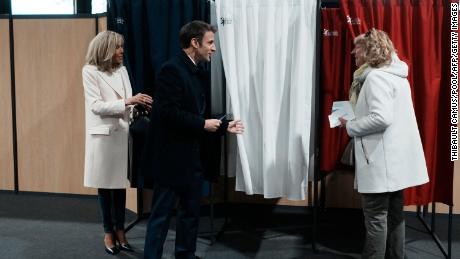 Il presidente francese Emmanuel Macron (al centro), accanto alla moglie Brigitte Macron (a sinistra), parla con un residente prima di votare domenica al primo turno delle elezioni presidenziali.