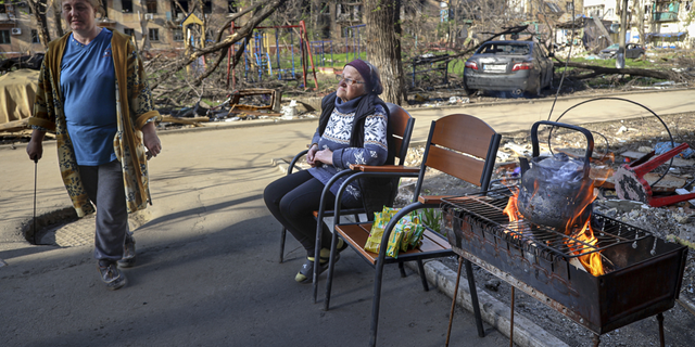 Le donne locali si radunano all'ingresso di un condominio distrutto a Mariupol, in Ucraina, martedì 26 aprile.