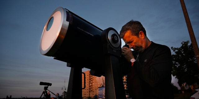 Robert Burgess, capo astronomo del Maine meridionale, ha installato un telescopio con filtri solari per guardare un'eclissi parziale dall'East Party a Portland giovedì 10 giugno 2021.