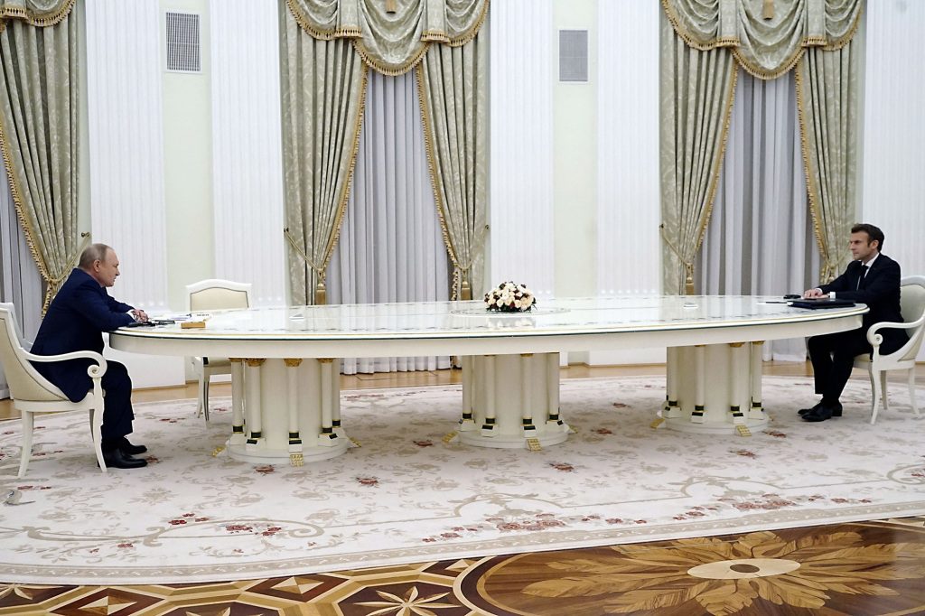 Putin e Marcon seduti uno di fronte all'altro a un tavolo a Mosca