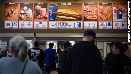 I clienti aspettano in fila per ordinare i cartelli sottostanti per un set di Hot Dog e Soda da $ 1,50 da Costco Kirkland.