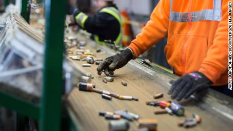 I dipendenti smistano le batterie che si muovono lungo un nastro trasportatore in un impianto di riciclaggio.