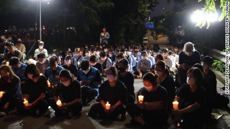 Una piccola folla tiene una veglia a lume di candela a Seoul l'11 agosto per commemorare la morte di una famiglia dopo che la loro casa è stata allagata l'8 agosto.