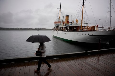Un pedone si protegge con un ombrello mentre cammina lungo il lungomare di Halifax venerdì.