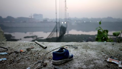 Una scarpa giace vicino a un ponte sospeso danneggiato a Morbi, in India, il 1 novembre 2022. 