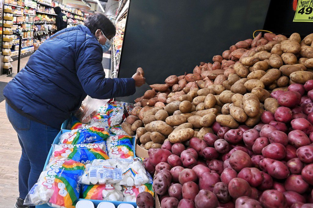 Una donna distribuisce patate in un negozio di alimentari.